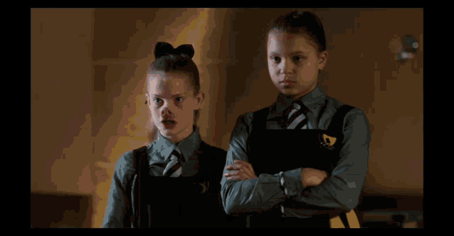 two girls wearing school uniforms with a yellow emblem on their shirts