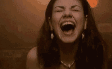 a woman is laughing with her mouth open and her eyes closed .