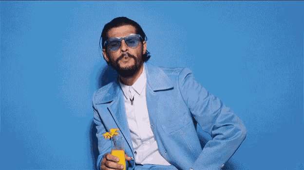 a man in a blue suit is drinking a yellow bottle