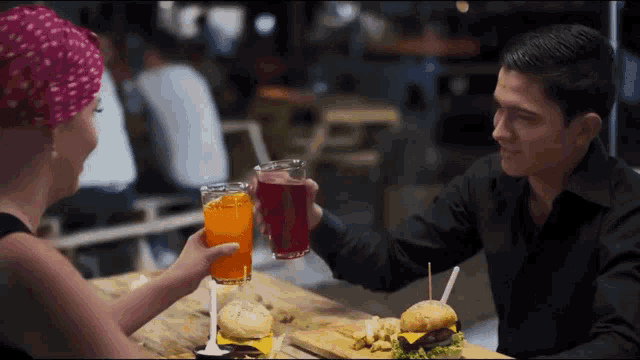 a man and a woman are toasting with drinks at a table