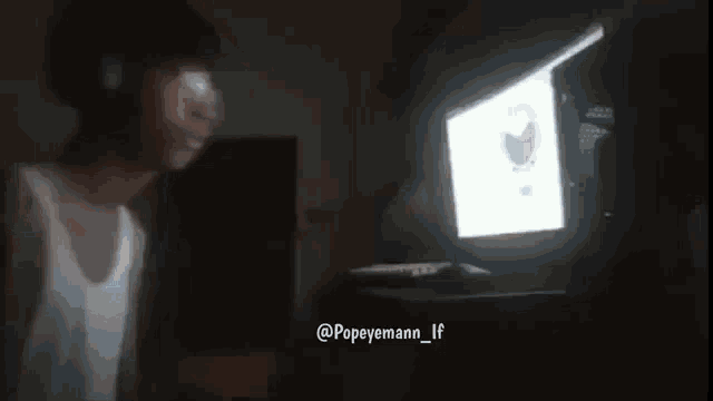 a person is standing in front of a computer screen with a picture of popeye on it .