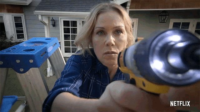 a woman is holding a drill in front of a netflix ad