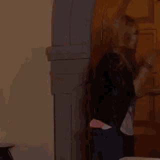 a woman in a leather jacket is standing in front of a wooden door .