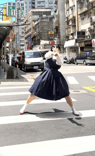 a woman in a blue dress is crossing the street in front of a sign that has the number 13 on it