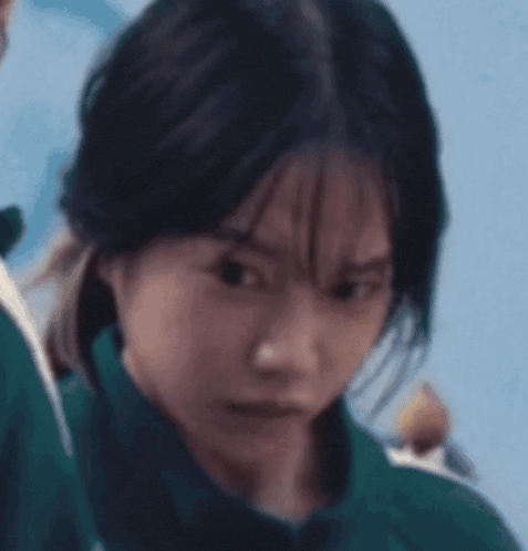 a close up of a woman 's face with a green jacket on .
