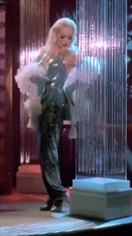 a woman in a black dress and white gloves is dancing