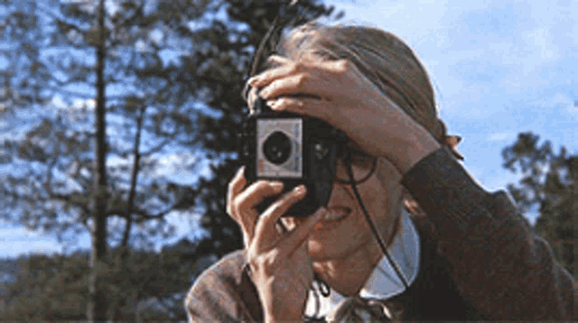 a woman is taking a picture with an old fashioned kodak camera