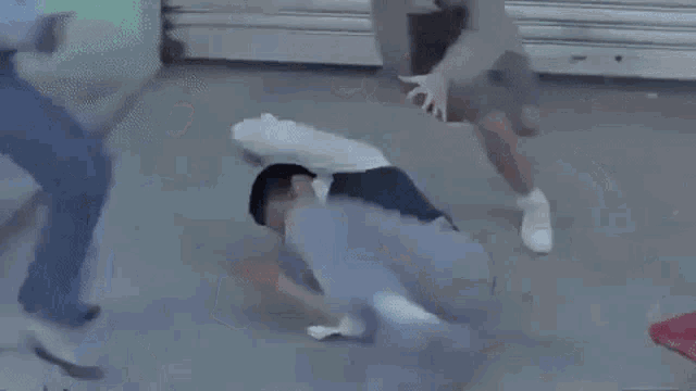 a group of people are fighting on the ground on the street .