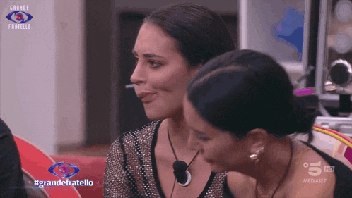 two women are sitting next to each other with the words grande fratello on the bottom