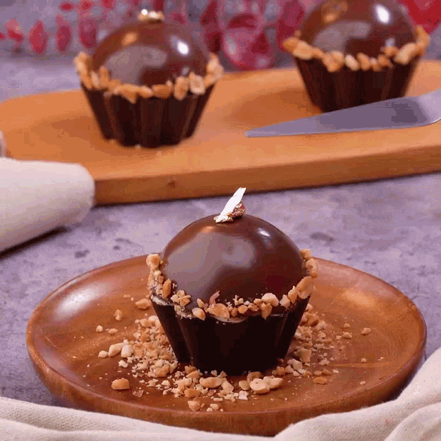 a chocolate cupcake on a wooden plate with nuts