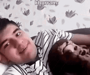 a man is laying on top of another man on a couch and smiling .