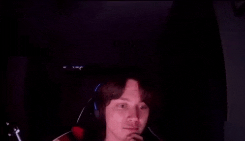 a man is wearing headphones and making a funny face in the dark .