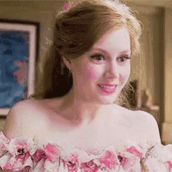a woman is wearing a pink floral dress and smiling in a room .