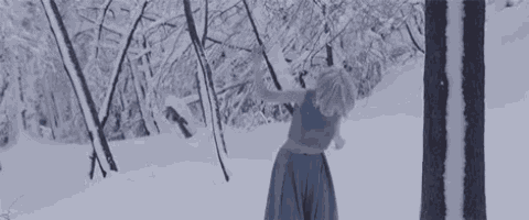 a woman in a blue dress is dancing in the snow in a forest .