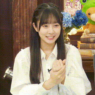 a girl with long hair is clapping her hands in front of a stuffed animal and a vase of flowers .