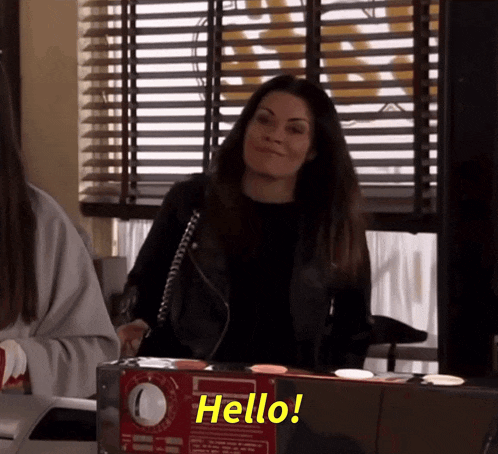 a woman is standing in front of a microwave and says hello