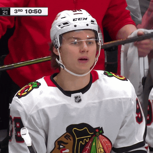 a hockey player wearing a white ccm helmet looks at the camera