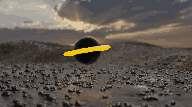 a black ball with a yellow ring around it is floating in the air