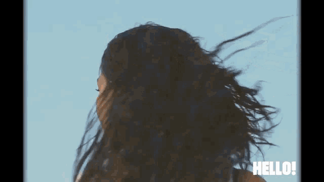 a woman 's hair is blowing in the wind and the words hello are visible