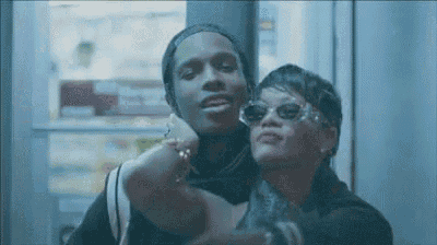 a man and a woman are posing for a picture together . the woman is wearing sunglasses .