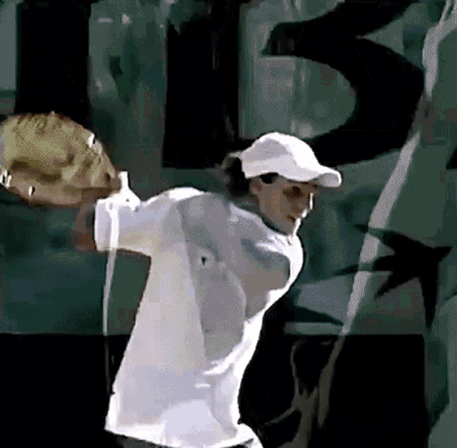 a man in a white hat is holding a tennis racket