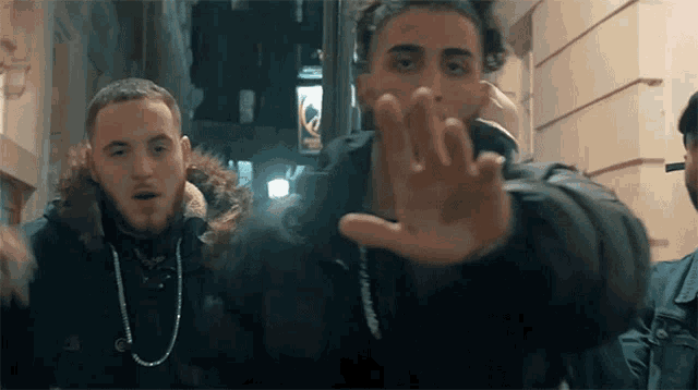 two men are standing next to each other and one of them is wearing a black jacket