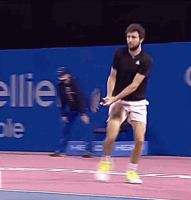 a man is swinging a tennis racket on a tennis court in front of a wall that says ellie