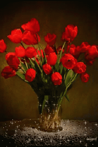 a vase filled with red flowers sits on a table with sparkles