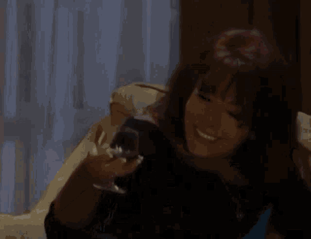 a woman is sitting on a couch holding a glass of wine in her hands .