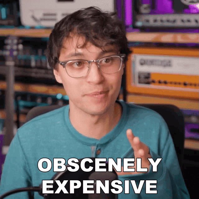 a man wearing glasses says obscenely expensive in front of a microphone