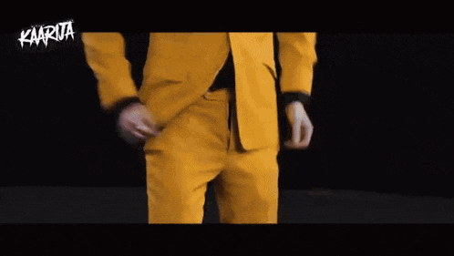 a man in a yellow suit and black shoes is standing in a dark room .