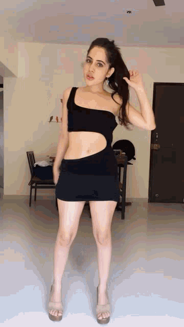 a woman is standing in a room wearing a black dress