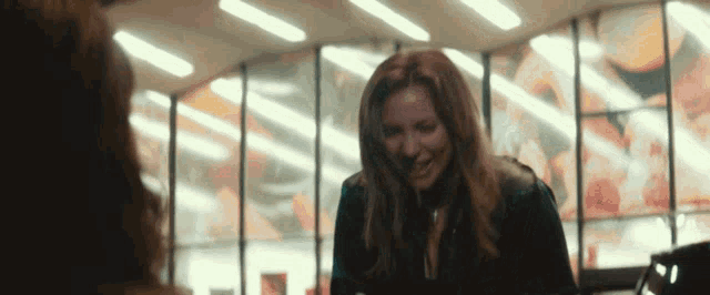 a woman with long hair is smiling in a room with a lot of windows