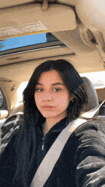 a woman is taking a selfie in the back seat of a car .