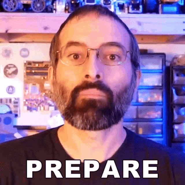 a man with a beard wearing glasses and a black shirt says prepare