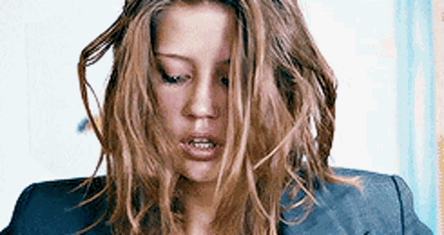 a close up of a woman with messy hair wearing a jacket .