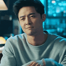 a man in a blue sweater is sitting at a table in a restaurant .