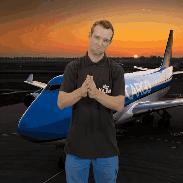 a man in a klm cargo shirt stands in front of an airplane