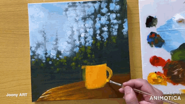 a person is painting a picture of a yellow cup on a table