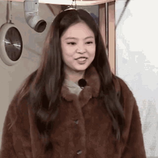 a woman wearing a brown fur coat is smiling and looking at the camera