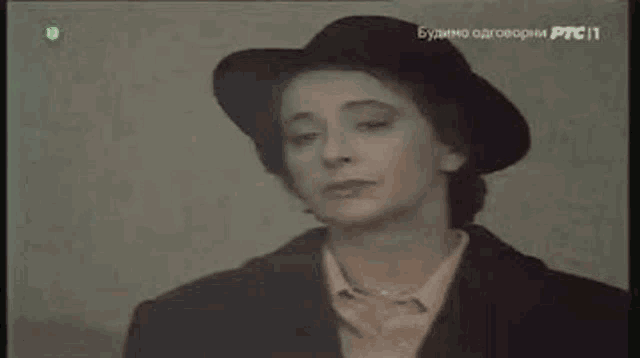 a woman is wearing a hat and a jacket and looking at the camera .