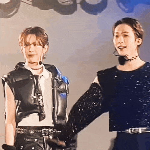 a couple of men are holding hands on a stage and one of them is wearing a choker .
