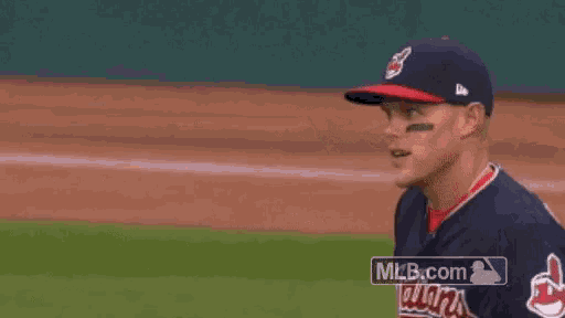 a man in a baseball uniform is pointing at something on the field .