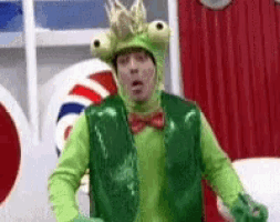 a man in a frog costume with a crown on his head is standing in a room .