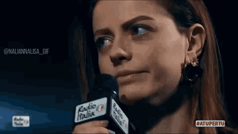 a woman is holding a microphone and making a face .