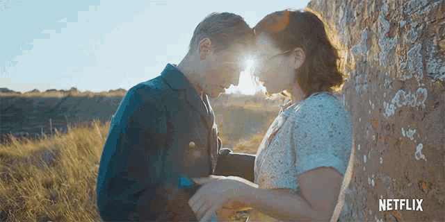 a man and a woman are kissing in front of a brick wall with netflix written on it