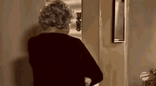 a woman is standing in a hallway looking out a door .