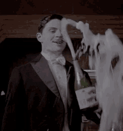 a man in a tuxedo is pouring a bottle of champagne into a glass .