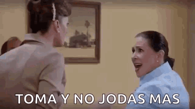 two women are standing next to each other in a room and talking in spanish .