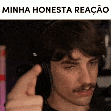 a man with a mustache is wearing headphones and pointing at the camera